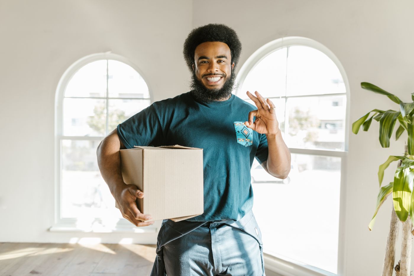 Persona sonriente cargando una caja durante una mudanza